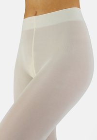 Pantimedias transparentes beige con una textura suave, que cuentan con una cinturilla ancha y suave, y detalles acanalados a lo largo de las piernas.