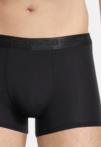 Boxer briefs neri realizzati in tessuto liscio, con una cintura larga e strutturata che presenta il logo del marchio, e un design aderente che arriva a metà coscia.