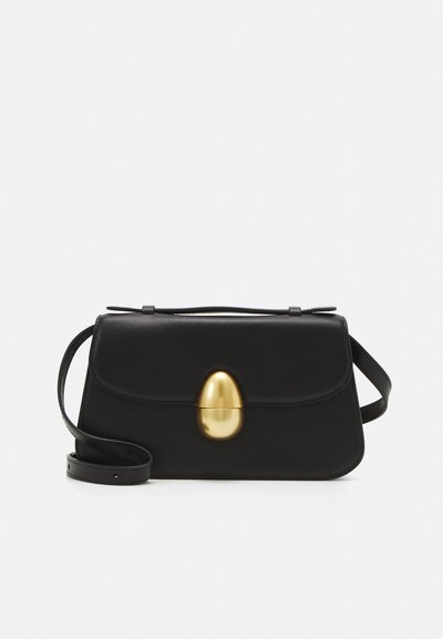 Black leather handbag with a gold oval clasp, flat rectangular shape, adjustable strap, and minimalistic design.