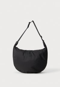 Bolso de hombro negro y suave en forma curva, con correa ajustable y cierre de cremallera; presenta un logo sutil en la parte frontal.