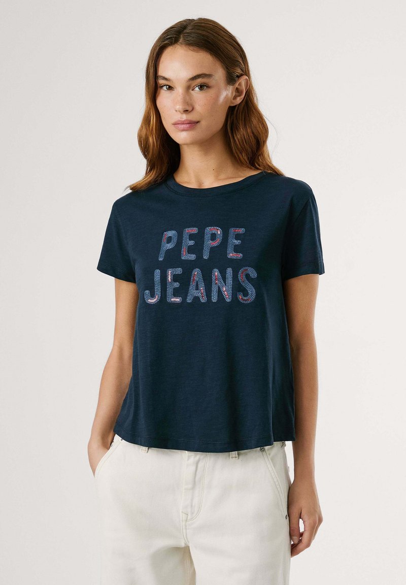 T-shirt di cotone blu navy con maniche corte, caratterizzato da una scritta in rilievo bianca e rossa "PEPE JEANS" centrata sulla parte anteriore.