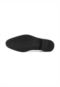 Suela de zapato de goma negra con rayas horizontales para tracción y una puntera redondeada. Las ranuras visibles y un perfil plano mejoran la estabilidad.