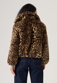 Bunda z umělé kožešiny s leopardím potiskem, vysokým límcem, zkráceným střihem a žebrovanými manžetami, v odstínech hnědé a černé.