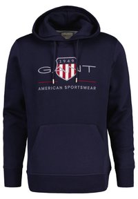 Felpa navy in cotone. Caratterizzata da una tasca a marsupio frontalmente, polsini a coste, cappuccio con cordino e un logo grafico con elementi rossi e bianchi.