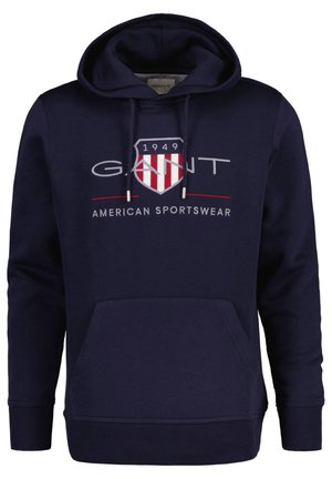 Sweatshirt bleu marine en coton. Il dispose d'une poche kangourou à l'avant, de poignets côtelés, d'une capuche avec cordon de serrage et d'un logo graphique avec des éléments rouges et blancs.