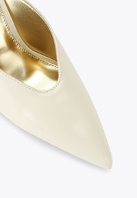 Crème leren puntige schoen met een uitsnijdontwerp; heeft een gladde buitenkant en een glanzende gouden binnenvoering.