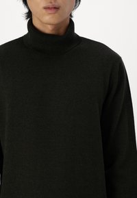 Czarny sweter z golfem wykonany z miękkiego, textured materiału. Posiada dopasowany kołnierz i długie rękawy. Prosty, nowoczesny design.