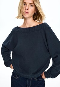 Mörk marinblå off-the-shoulder sweatshirt med ribbad halsringning och ärmar, med en avslappnad passform och mjuk textilstruktur.