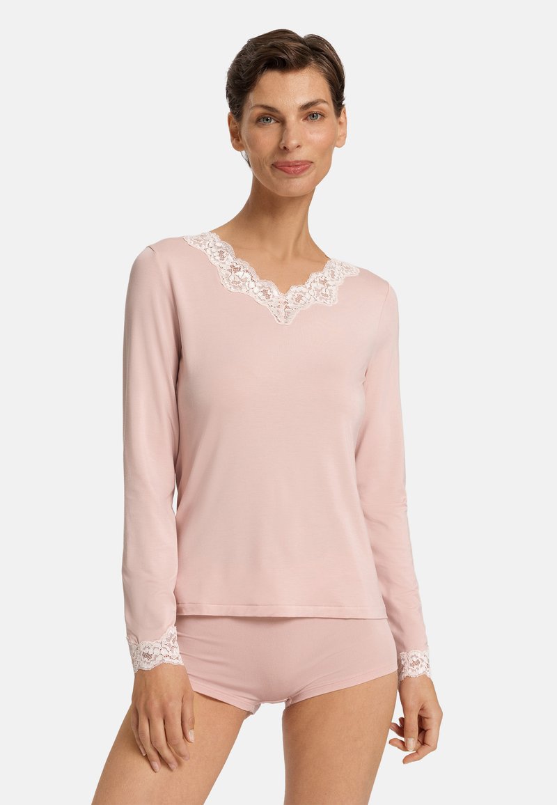 Top de manga larga rosa claro con escote de encaje y detalles de encaje en las mangas, combinado con unos pantalones cortos a juego con acentos de encaje. Textura de tela suave.