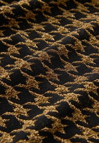 Tissu noir avec un motif texturé d'étoiles dorées, présentant une finition métallique scintillante et un tissage lisse.