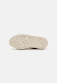 Suela de zapato de goma color crema con un patrón texturizado, que presenta un borde liso y un diseño de agarre triangular. Sin elementos de marca visibles.