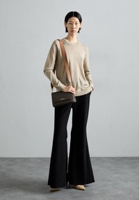 Beige long-sleeve sweater with a crew neckline, paired with black wide-leg trousers. Brown crossbody bag with a subtle pattern, nude heels.
