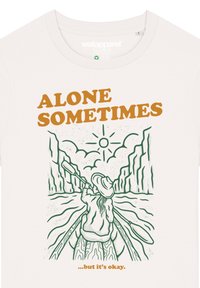 Cremfarbenes T-Shirt mit grünem Linienkunstwerk einer Person im Kajak und dem Text „MANCHMAL ALLEIN... aber das ist in Ordnung.“ in Orange.