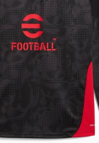 Maillot de football noir avec un motif texturé et à pois. Présente des accents rouges et un logo avec le mot "FOOTBALL" en lettres grasses. Fabriqué en tissu respirant.