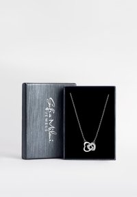 Sølv halskæde med sammenflettede hjertevedhæng, præsenteret i en sort, fløjlbeklædt boks med en struktureret, grå yderside.