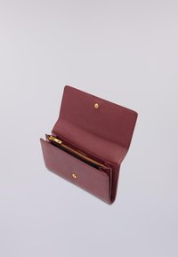 Portafoglio bordeaux con una finitura testurizzata, hardware dorato e una tasca con chiusura a zip. Presenta una chiusura con pattina e diversi scomparti per carte.