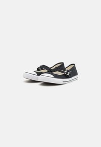 Scarpe slip-on nere in tela con punte e suole in gomma bianca; presentano fasce incrociate con fibbie per una vestibilità sicura.