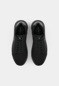 Zwarte sneakers van stof met een gladde afwerking, voorzien van platte veters, een logo op de tong en een afgerond te ontwerp.