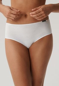 Białe bawełniane majtki hipsterki z elastycznym pasem i miękką fakturą, z małą czarną metką po boku.