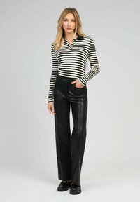 Polo à manches longues noir et blanc à rayures associé à un pantalon large en similicuir noir taille haute et des chaussures noires épaisses.