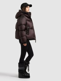 Puffer jacket in dark purple with a hood, paired with black leggings and chunky black boots featuring a gray label and laces.