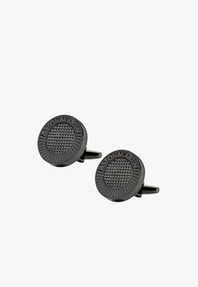 Boutons de manchette ronds noirs présentant une surface texturée avec un motif en losange, gravés de "ASTON MARTIN" autour du bord. Finition métallique.
