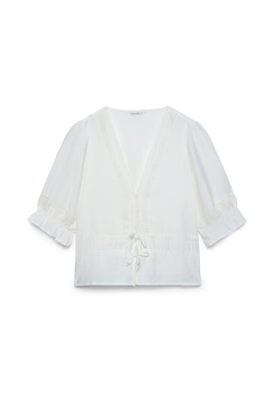 Blouse blanche à col en V avec manches bouffantes 3/4, couture décorative le long de l'encolure et des manches, et un lien à nouer devant à la taille.