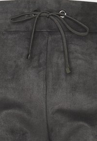 Černé semišové kalhoty s měkkou texturou a stahovací šňůrkou, se soklovými a koncovými detaily pro upevnění pasu.