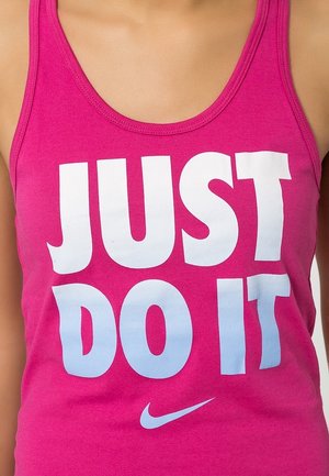 Różowy top na ramiączkach z białym tekstem w gradientowym stylu "JUST DO IT" z małym logo Nike na dole. Gładki materiał bawełniany.