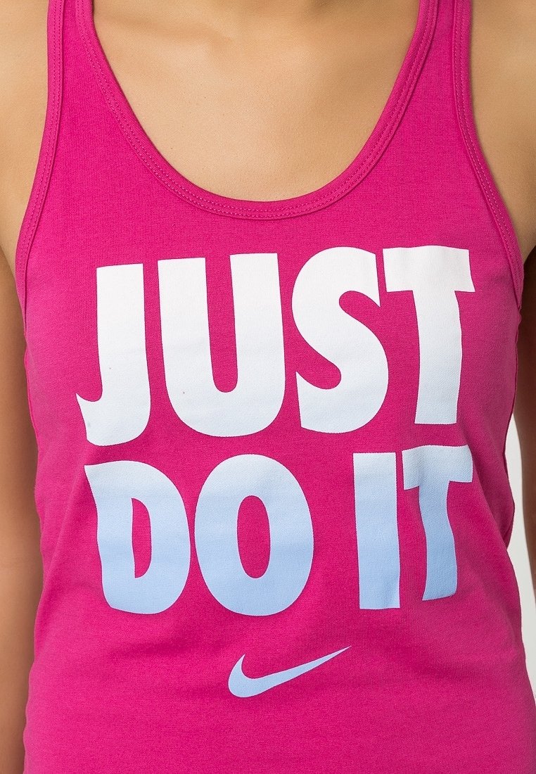 Top in cotone rosa con testo bianco in gradiente che recita "JUST DO IT", con un piccolo logo Swoosh Nike in basso. Materiale in cotone morbido.