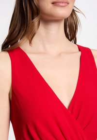 Robe portefeuille rouge avec un décolleté en V profond et des bretelles larges, réalisée en tissu doux avec une texture lisse.