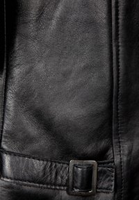 Schwarzes Leder mit glatter Textur. Verfügt über einen auffälligen Gurt, der mit einer quadratischen Metallschnalle gesichert ist. Nahtdetails sind sichtbar.