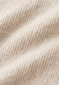 Primo piano di un morbido tessuto a maglia beige con strisce verticali texturizzate e leggere ombre che esaltano la profondità e la trama del materiale.