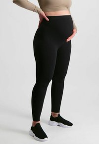 Zwarte geribde legging met hoge tailleband, voorzien van een aansluitend ontwerp en gecombineerd met zwarte instap schoenen.