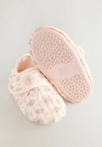 Chaussons rose matelassés avec motif floral, bande velcro et semelle en caoutchouc texturé avec un design de fleurs, adaptés à une utilisation intérieure.