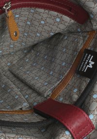 Braunes Futter mit Sternmuster und hellblauen Akzenten, versehen mit roten Lederverzierungen und einem braunen Lederschild, in einer Reißverschlusstasche.