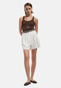 Brun ribbad linne, vita randiga högmidjade shorts med veck, svart bälte med rund spänne och svarta mesh-lägenheter.