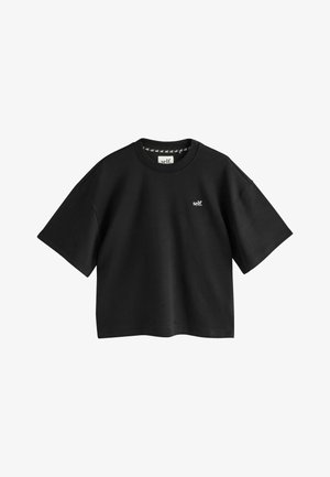 Black cropped t-shirt with short sleeves, made of cotton. Features a small white logo and a round neckline. Smooth texture with minimal detailing.