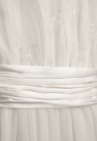 Weißes Kleid mit zarter Blumenstickerei und Pailletten. Verfügt über einen glatten, gerafften Taillenbund und sanfte, fließende Falten am Saum.