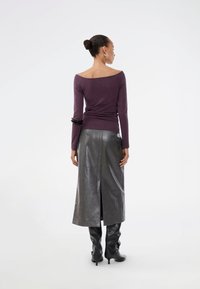 Long-sleeve, off-the-shoulder purple top paired with a high-waisted, glossy gray leather skirt. Black knee-high boots complete the look.