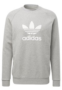 Grå sweatshirt av mjukt tyg med rund halsringning, raglanärmar och en stor vit Adidas-logotyp med tre ränder.