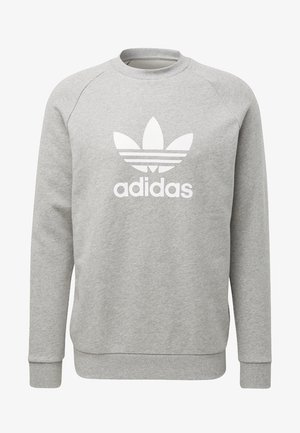 Szara bluza wykonana z miękkiego materiału, z okrągłym dekoltem, rękawami raglanowymi oraz dużym białym logo Adidas z trzema paskami.