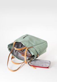 Groene stoffen rugzak met bruine leren banden, ritsopening aan de bovenkant en een geblokt interieur. Inclusief een klein grijs zakje met rode rits.
