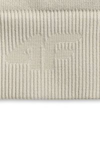 Tissu tricoté côtelé beige avec un logo tissé en relief représentant une tête d’animal stylisée et la lettre F.