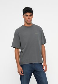 T-shirt grigio a maniche corte realizzato in cotone, con vestibilità morbida, scollo rotondo e piccolo logo dettagliato sul lato sinistro del petto.