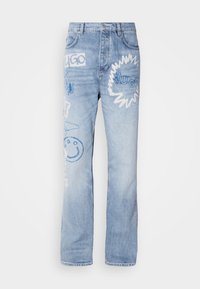 Light blue denim jeans with straight legs, featuring various embroidered designs in blue and white, including text and a smiley face.