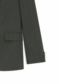 Dark green tailored blazer with a textured weave, single chest pocket, and four-button cuff detail. Smooth fabric finish.