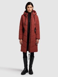 Pikowany płaszcz do kolan w ceglastym kolorze z kapturem, czarnymi akcentami, kieszeniami na zamek i zawieszką przy zamku. Nosi się go z czarnymi legginsami i wysokimi kozakami za kolano.