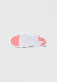 Λευκή σόλα αθλητικού υποδήματος με υφή από καουτσούκ, με ροζ στοιχεία. Ο σχεδιασμός περιλαμβάνει κυκλικά μοτίβα και διακριτικό κάλυμμα στη φτέρνα.