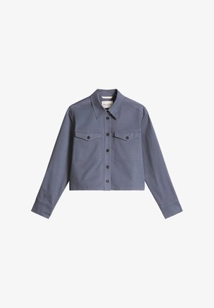 Giacca corta azzurra in cotone con chiusura frontale con bottoni, due tasche sul petto e maniche lunghe. Presenta bottoni scuri e una texture liscia.